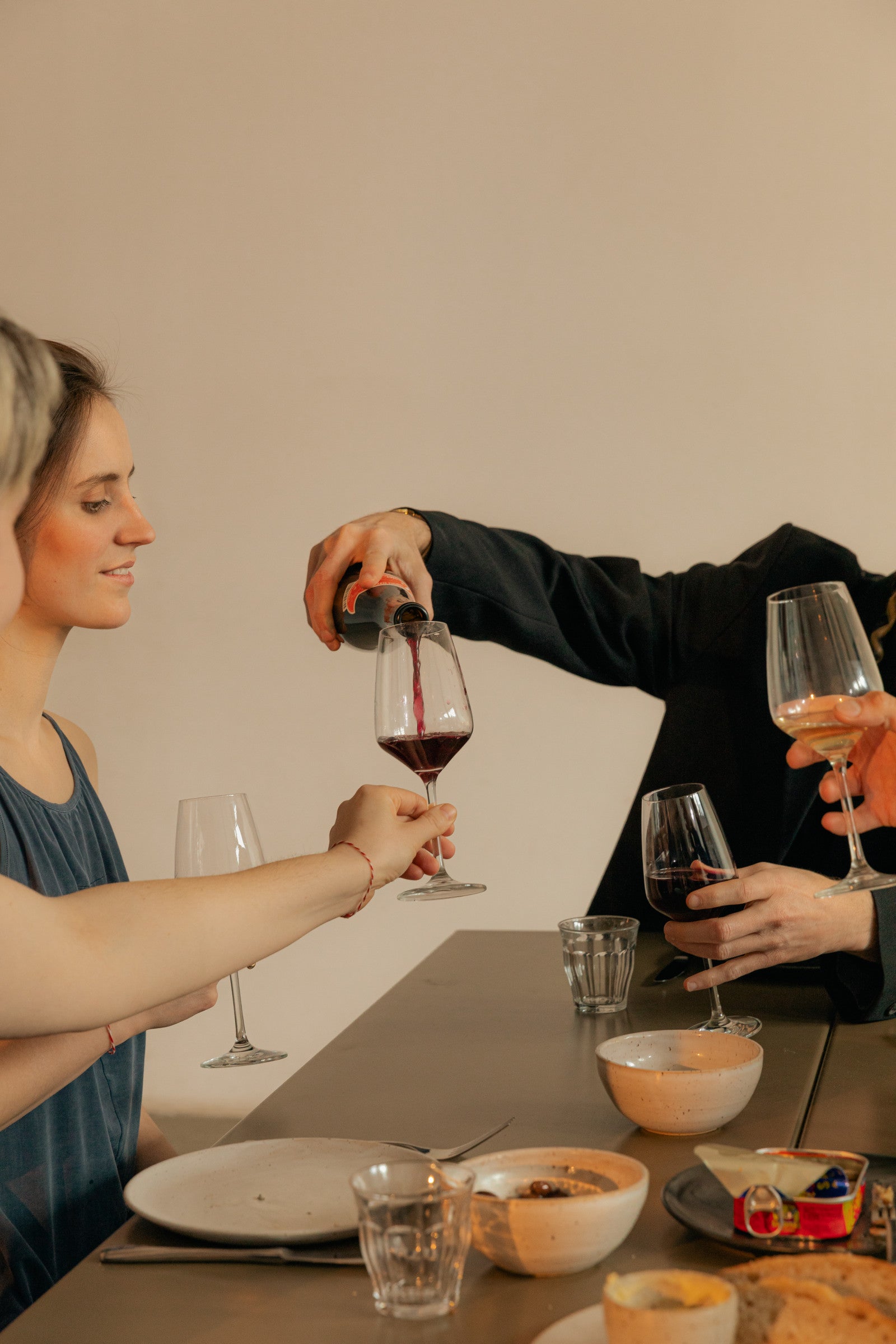 Friends sharing wine around a dinner table.